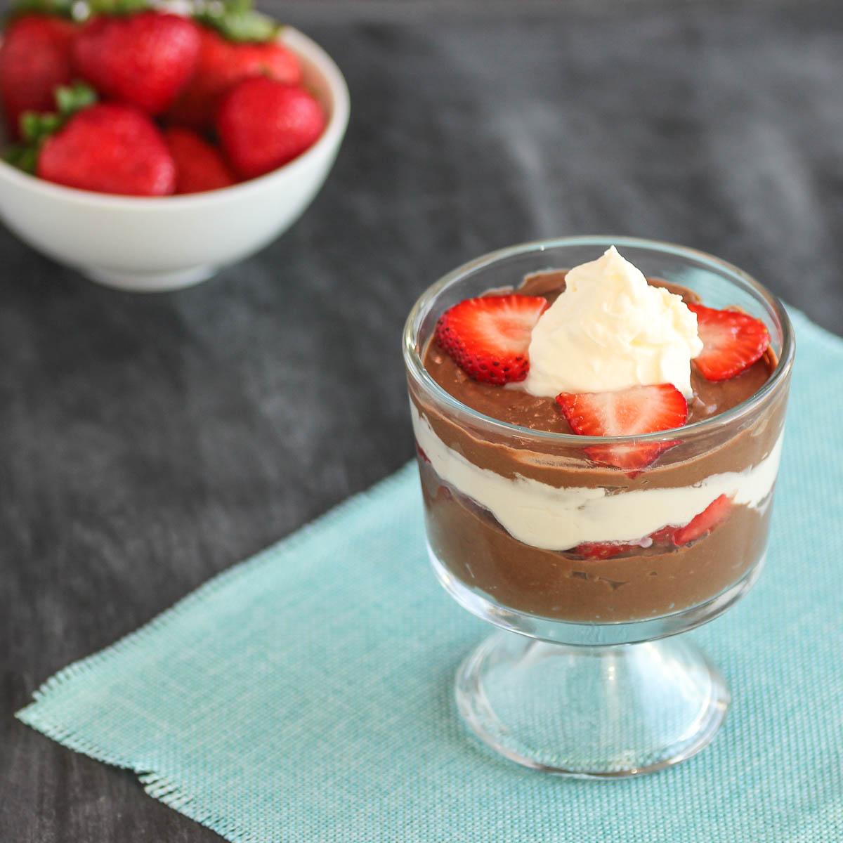 A creamy chocolate pudding with whipped cream and slice strawberry parfait.