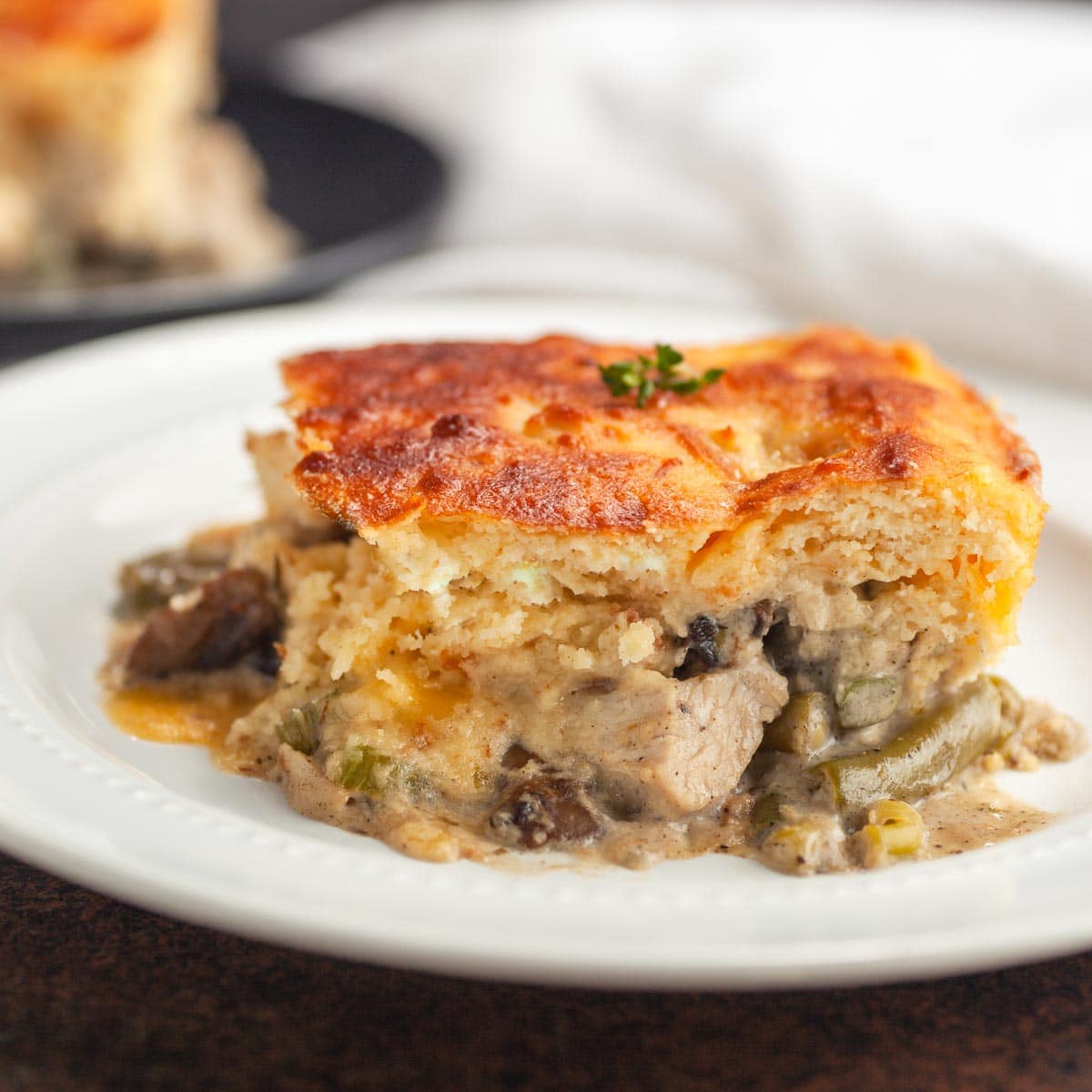 A slice of a chicken pot pie with a bacon biscuit crust.