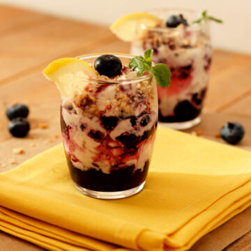 Two berry lemon and cream parfaits with granola on top.