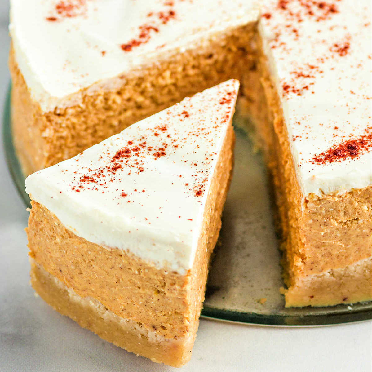 A slice of keto pumpkin cheesecake coming out of a whole cheesecake.