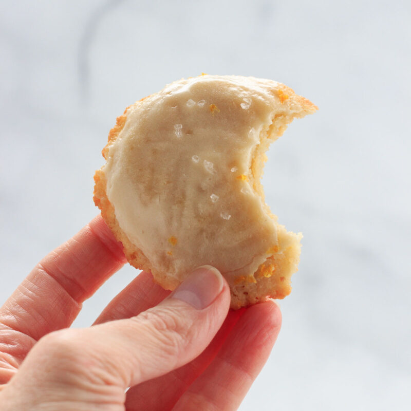 A low carb lemon iced cookie with a bite in it.
