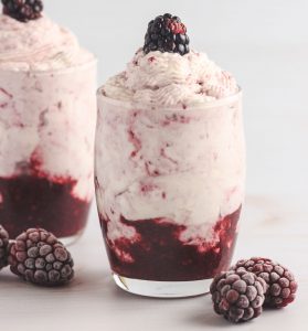 Two whipped creamy blackberry desserts in shot glasses.