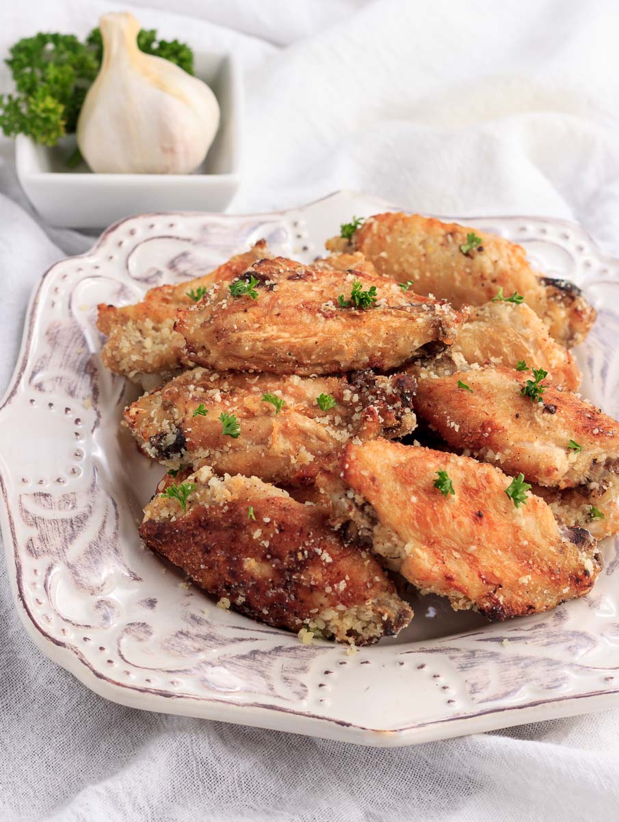 A stacked plate of chicken wingas with garlic & parmesan cheese.