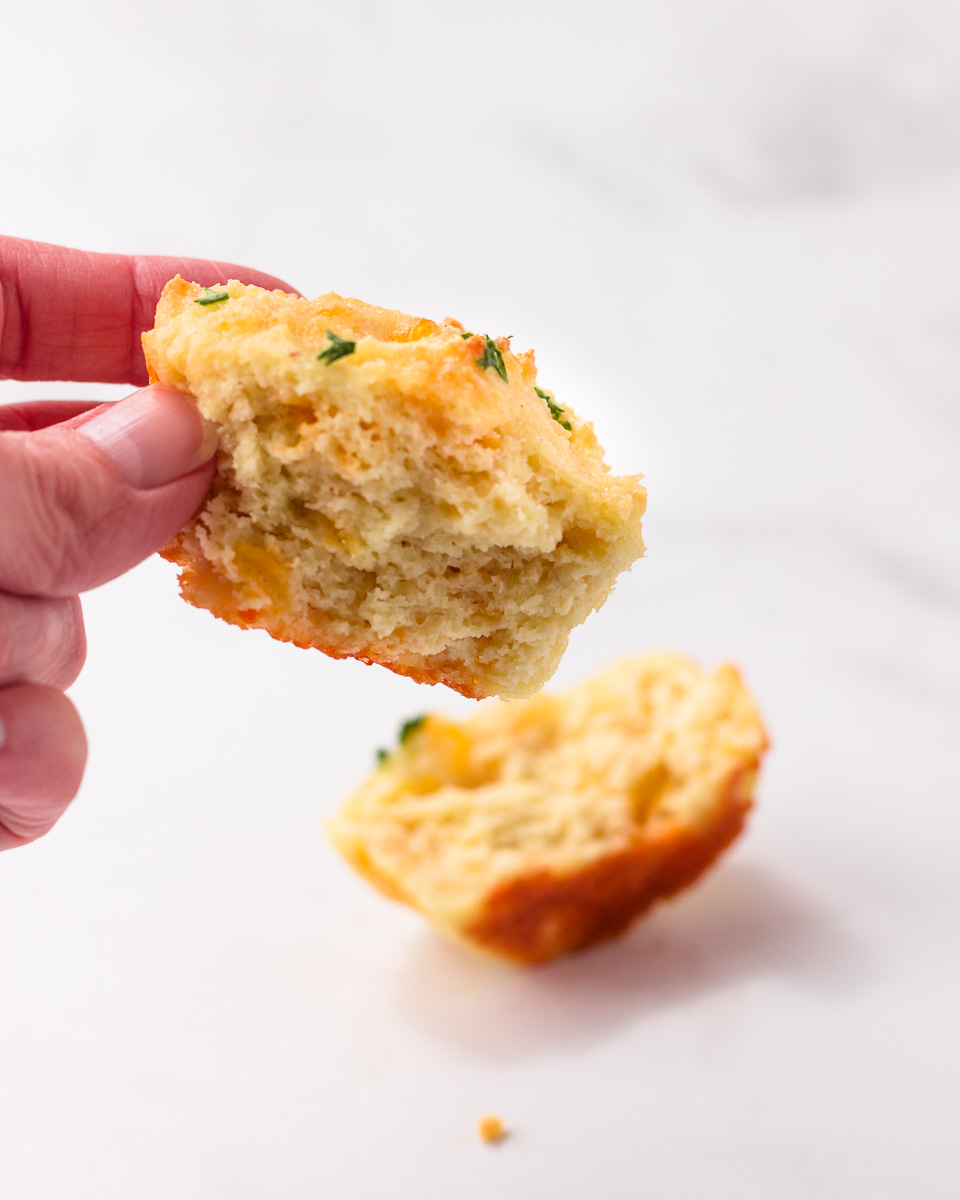 A keto garlic cheddar biscuit  cut open and half held in a hand.