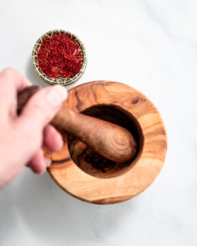 Grinding saffron threads into powder with a mortar and pestle.