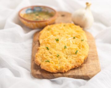 Low carb naan on a cutting board with a bowl of dipping herb oil.