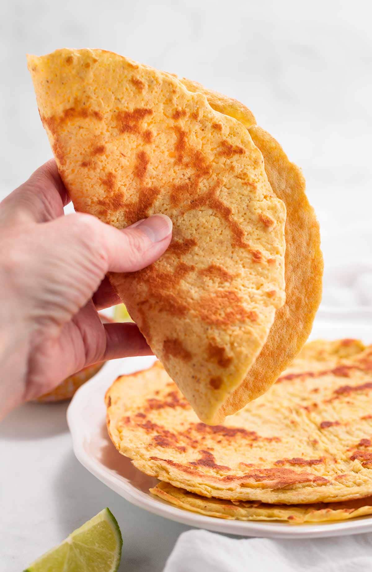 A hand folding a keto tortilla in half.