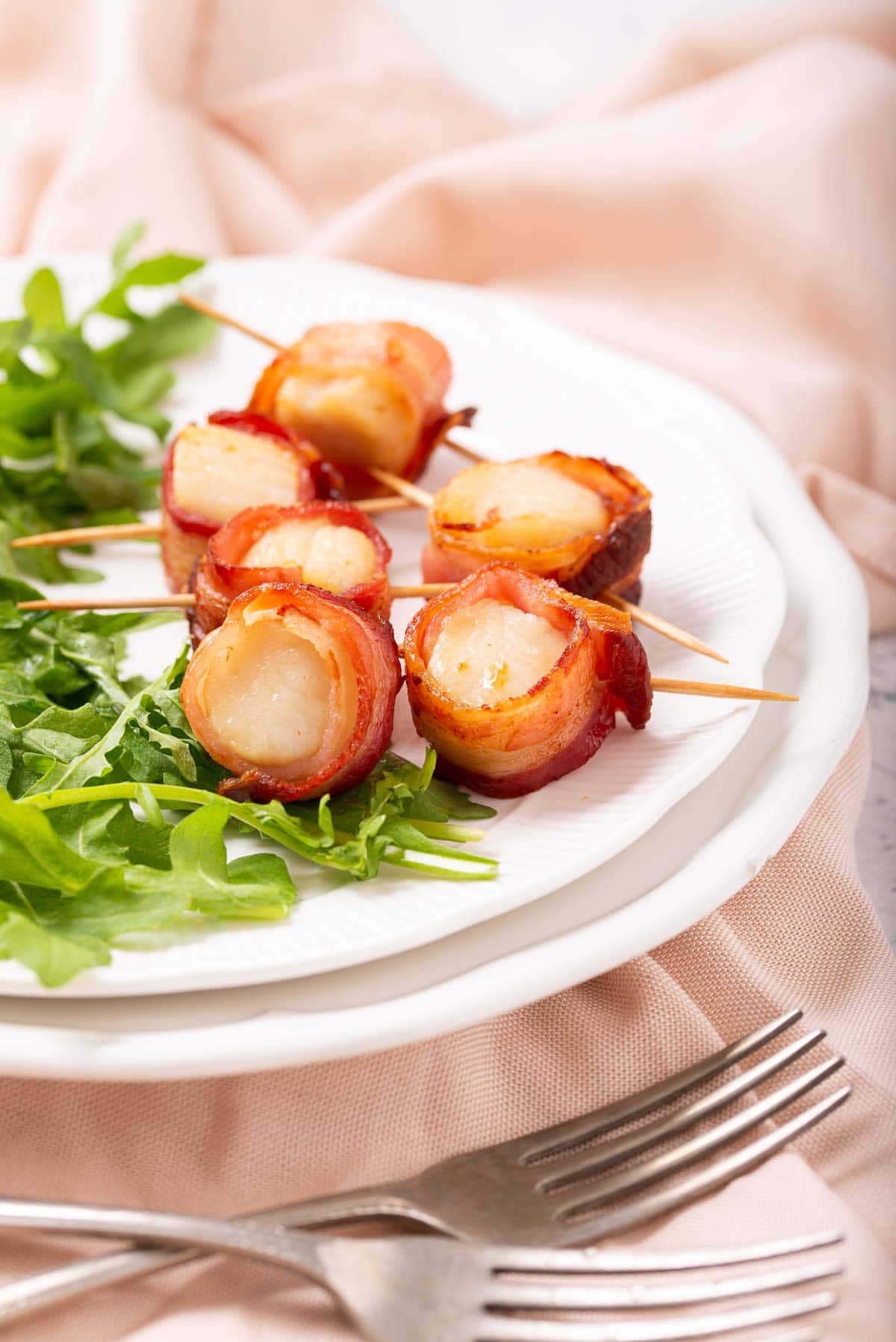 Bacon wrapped scallops on a bed of arugula