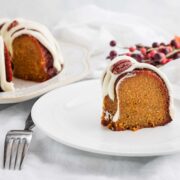 A slice of iced low carb pumpkin bundt cakke with the whole cake behind it.