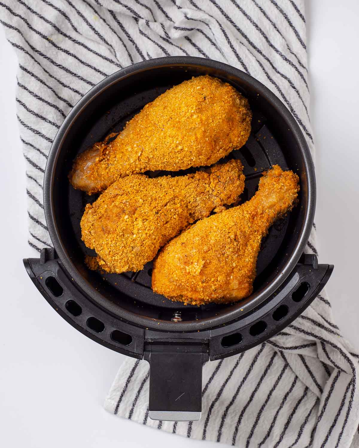 Placing the drumsticks into the air fryer.