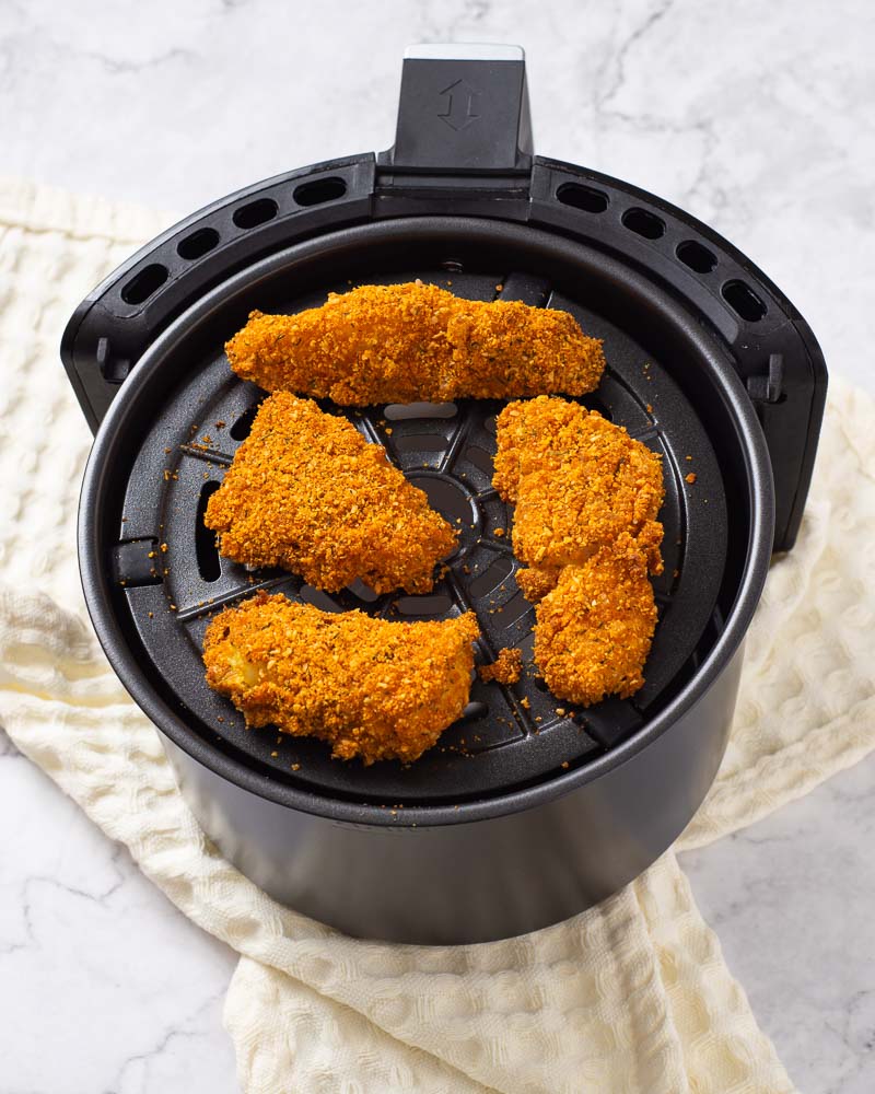 Placing the breaded fish sticks into the air fryer.