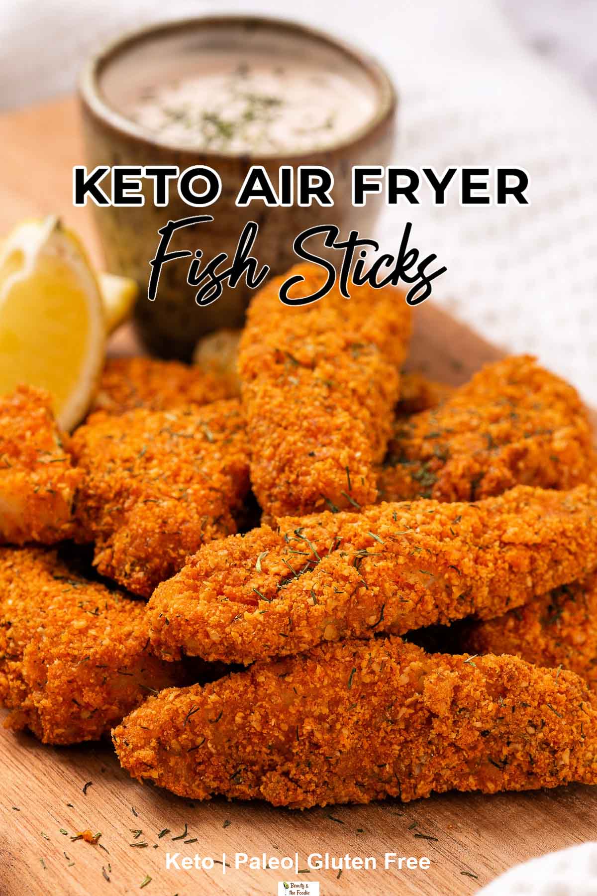 Air Fryer Fish sticks with a wedge of lemon and a pnch-bowl of tartar sauce on a cutting board.