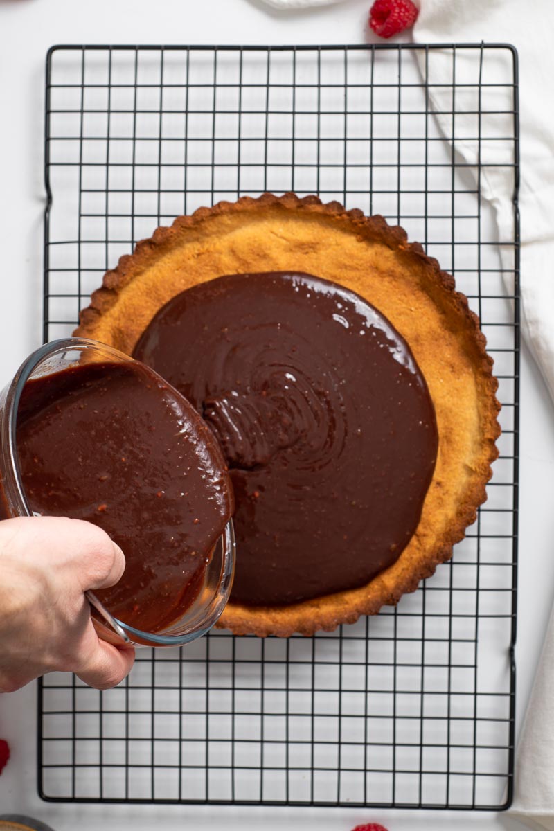 Pouring the chocolate ganache into the tart crust.