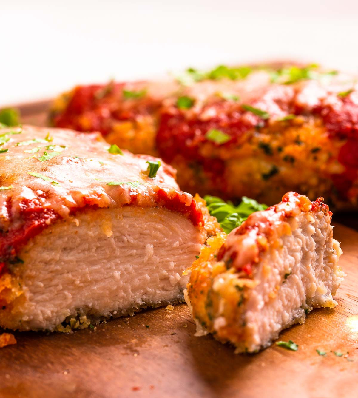 Two low carb breaded and air-fried chicken parmesan cutlets with marinara sauce and cheese.