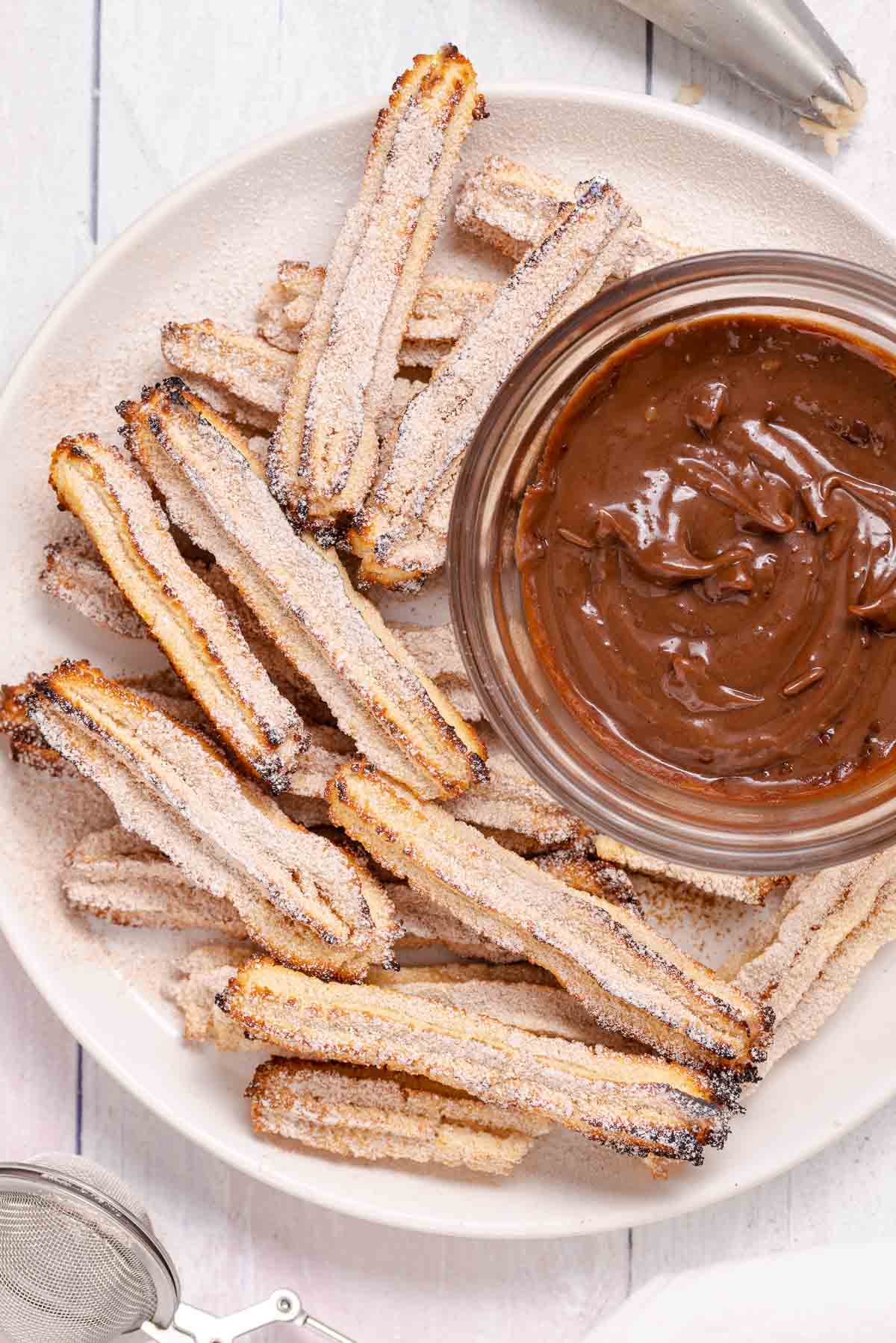 A plate of low carb churros with a bowl of chocolate dipping sauce.