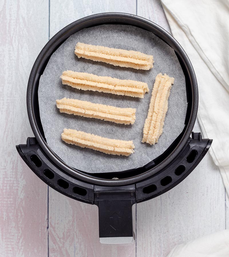 Piping the churros onto the parchment paper.