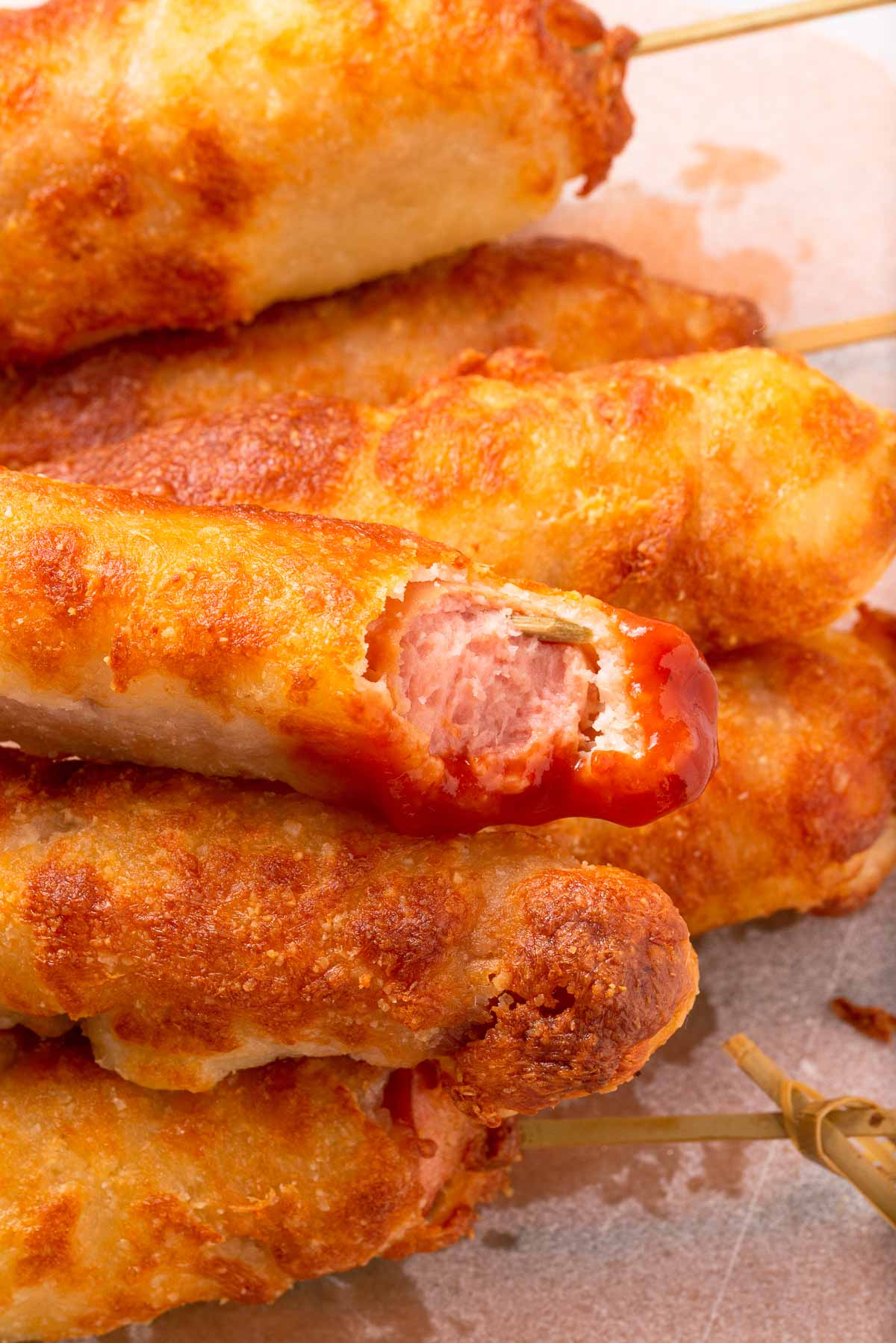 A stack of keto corn dogs with a bite in one of them.