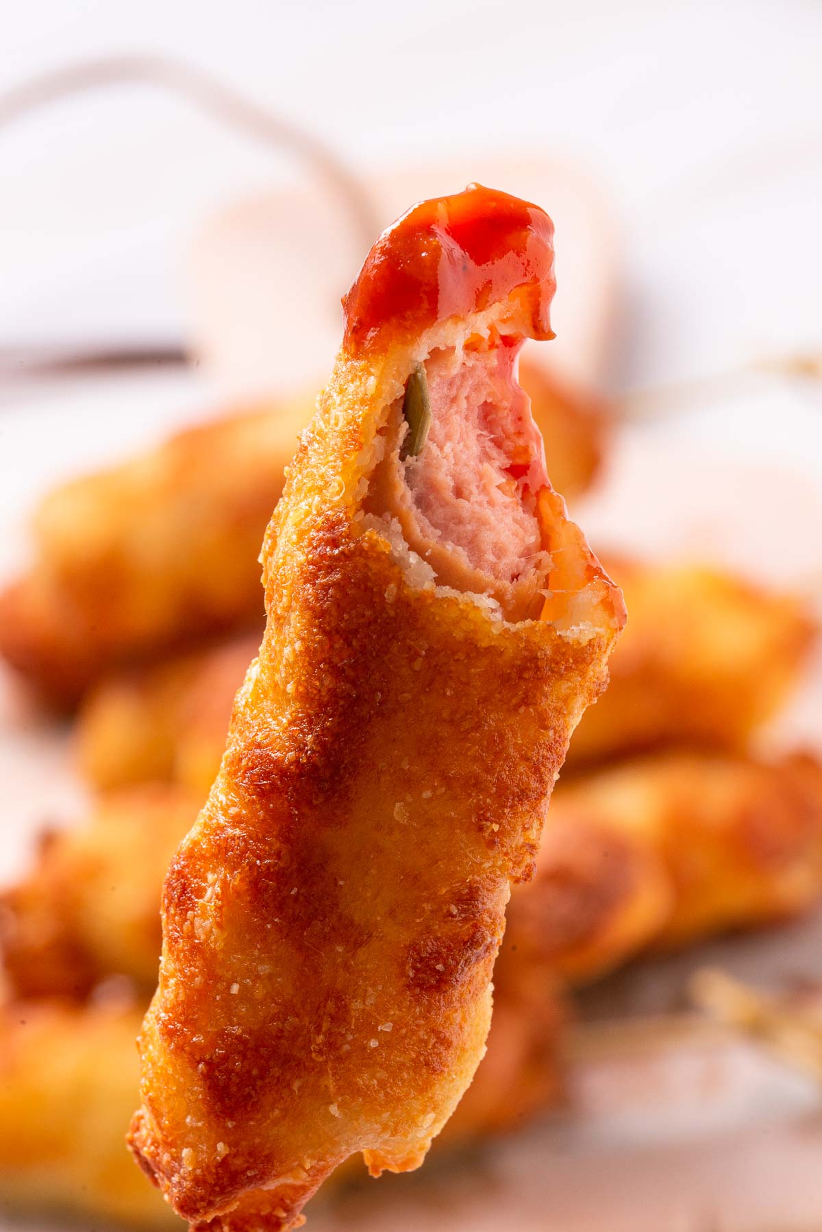 A keto corn dog with a bite out of it.