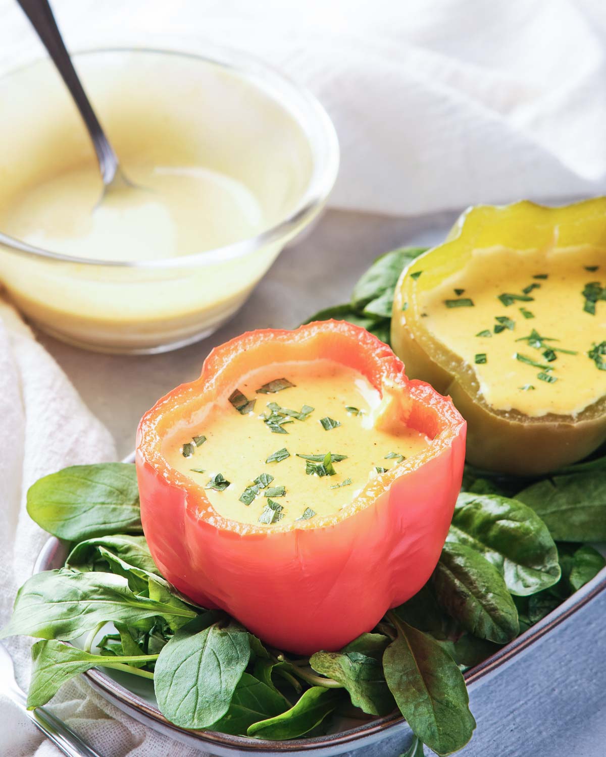 Two bell pepper cups with an egg isde and ttopped with hollindaise sauce.
