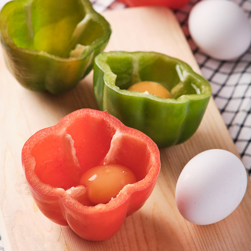 Cracking an egg into the bell pepper cups.