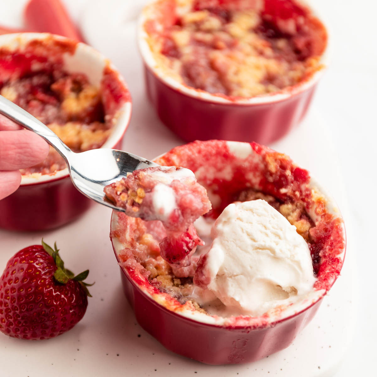 Strawbeery rhubarb crisp with a spoonful coming out of the crisp.