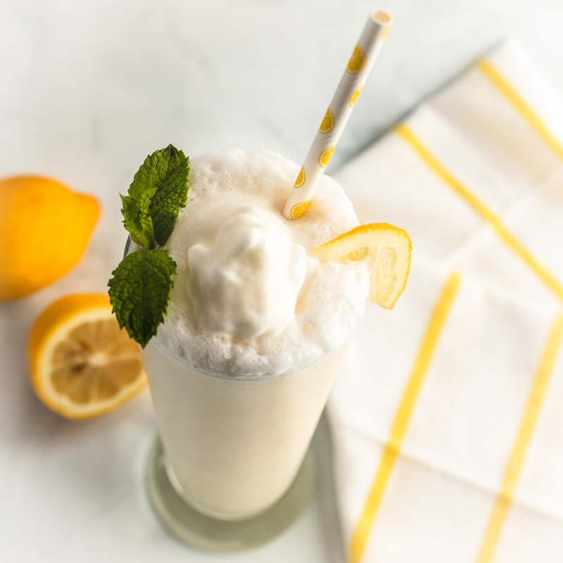 Garnishing frosty lemonade with whipped cream and mint leaves.