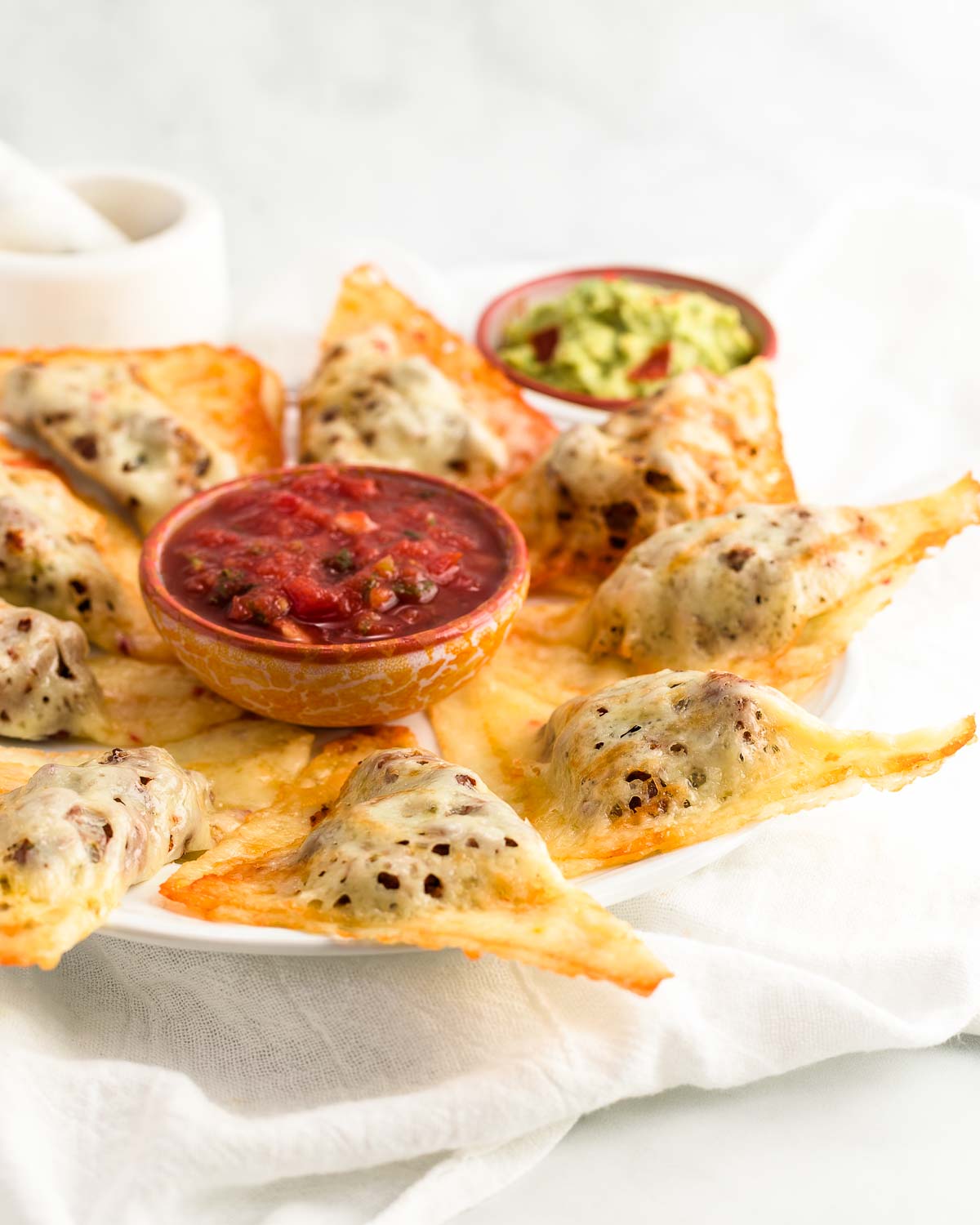 A platter of  keto pepper jack taco pockets with salsa and guacamole dips.