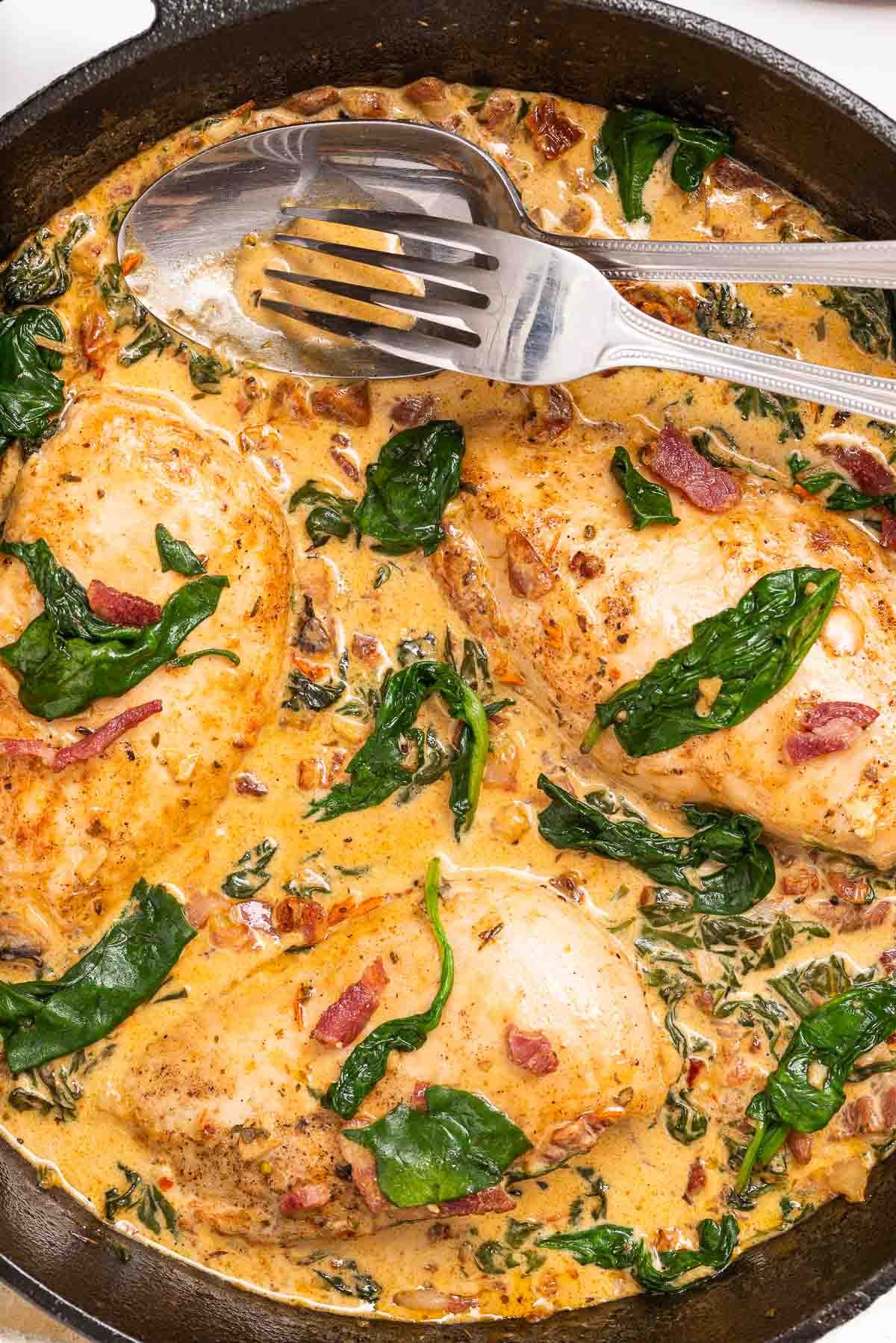 A pan with chicken, bacon, spinach and a creamy Tuscan sun-dried tomato sauce.
