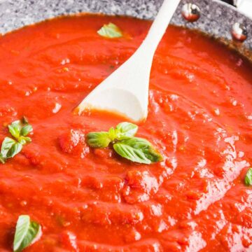 Stirring Italian marinara sauce in a deep pan.