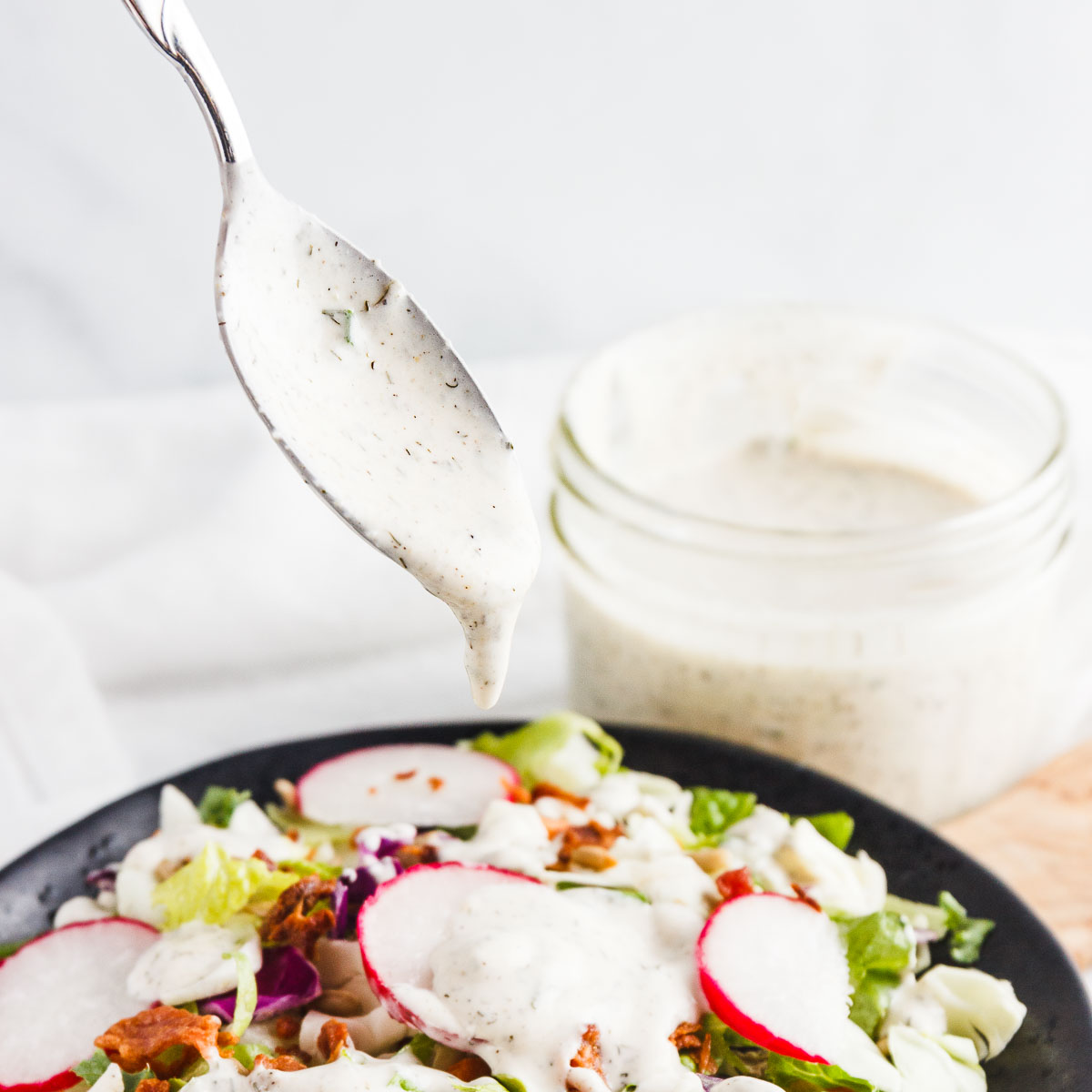Pouring ranch dressing over a salad.