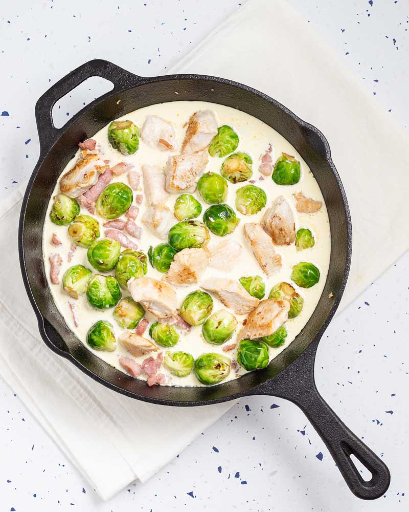 Adding the bacon, chicken and cream to the pan.