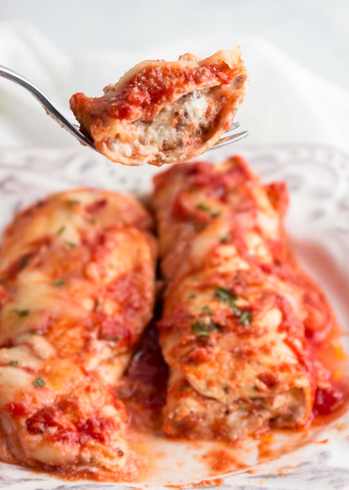 Two low carb beef and cheese manicotti rolls in sauce.