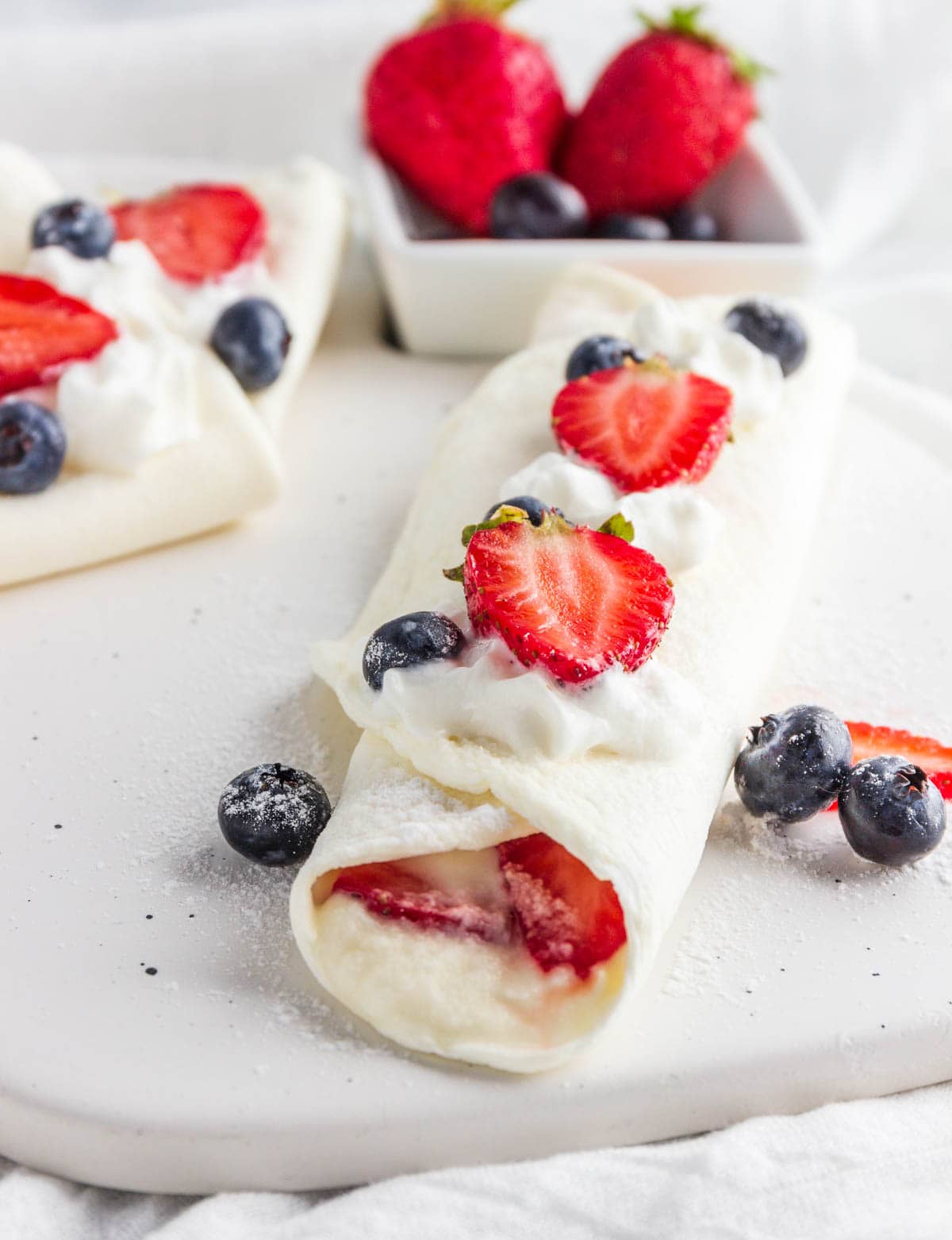 A stuffed crepe with cream and berries.