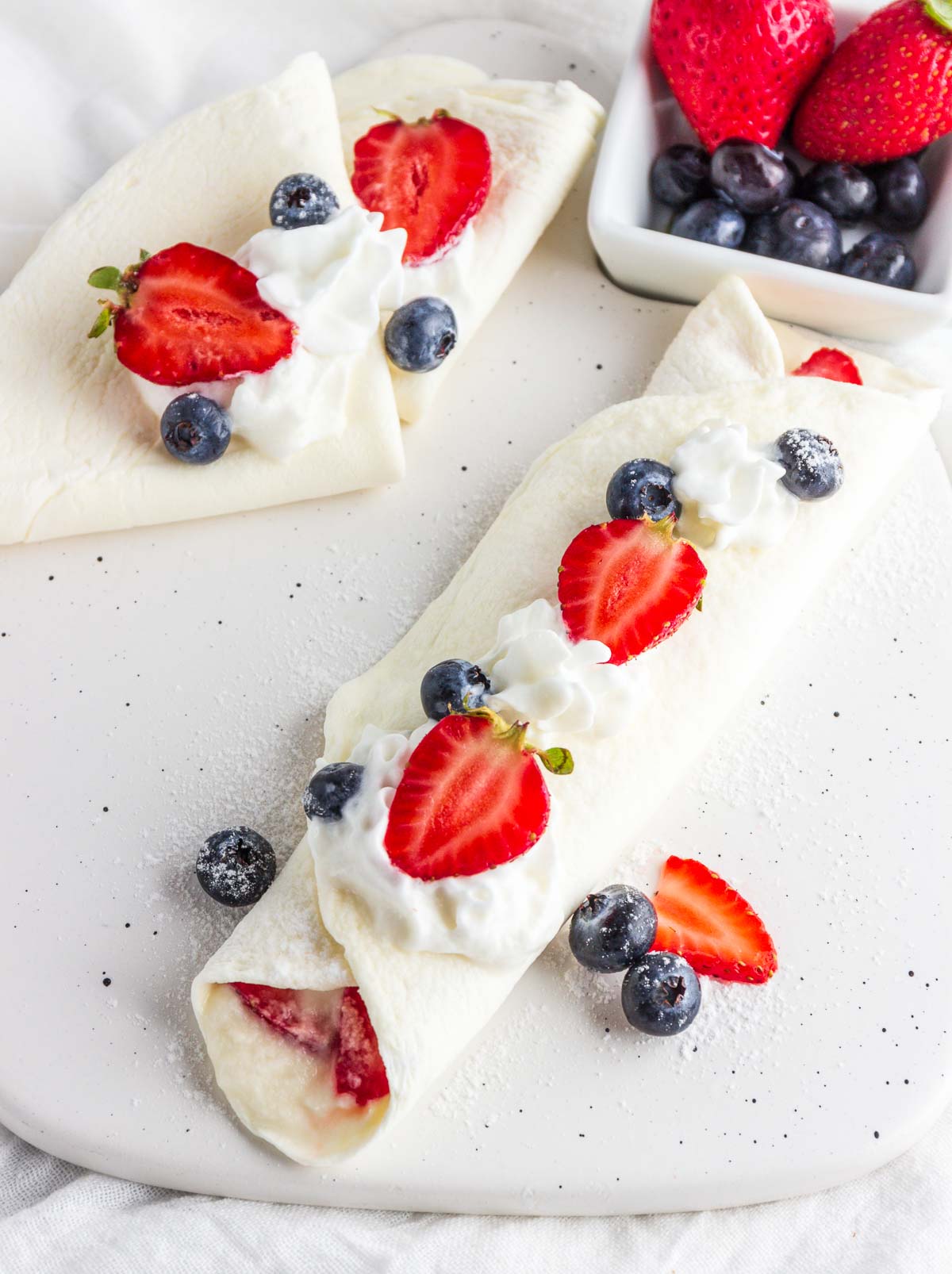 A stuffed crepe with cream and berries.