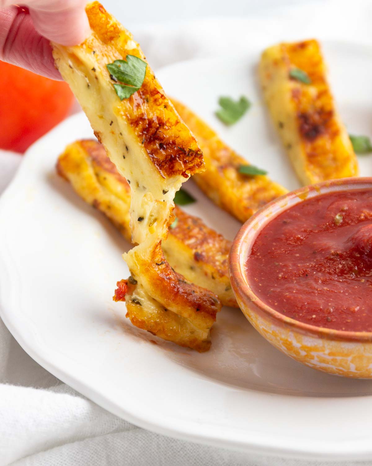 A pizza fried cheese stick abut to be dipped in sauce.