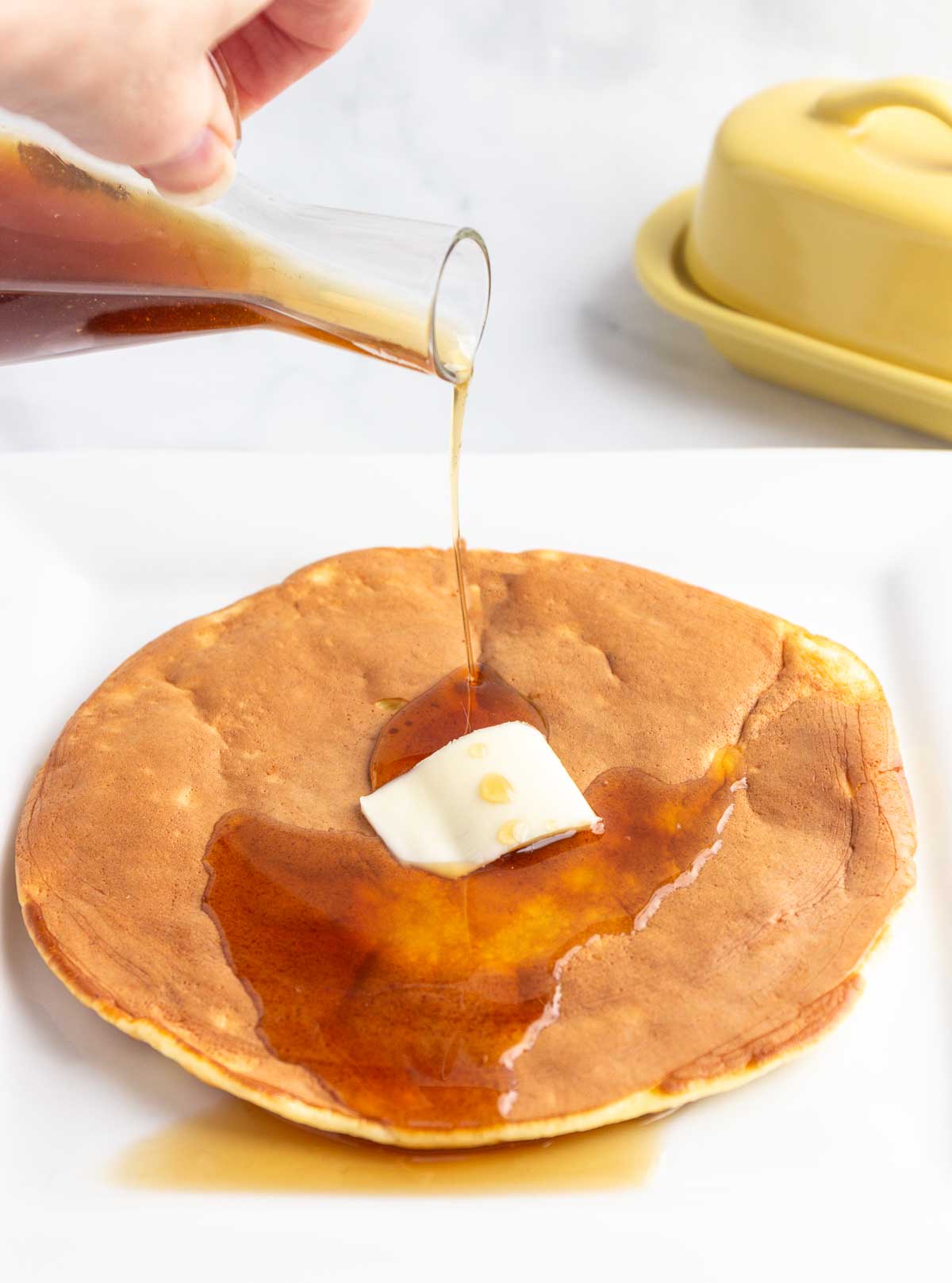A large single fluffy low-carb pancake with syrup being poured on top.