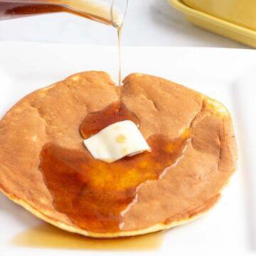 A large single fluffy low-carb pancake with syrup being poured on top.