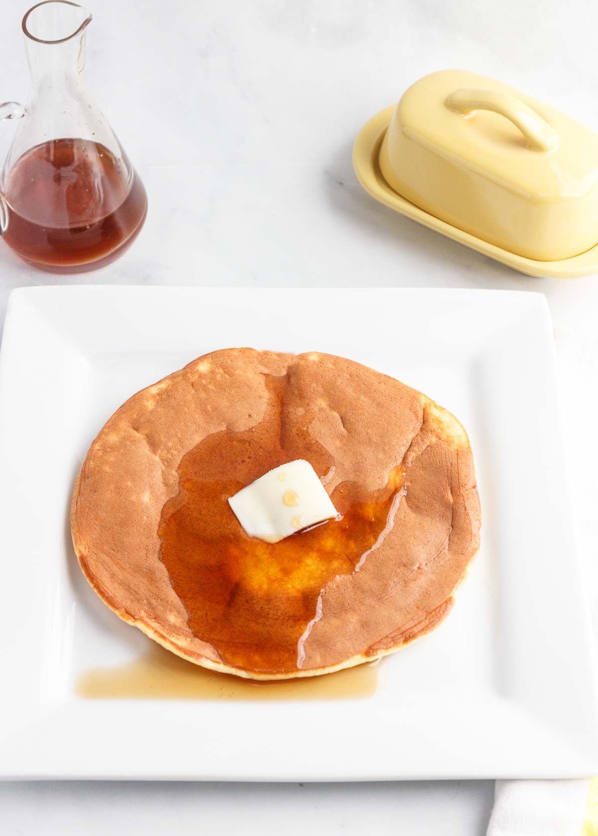 A keto big fluffy protein pancake that is low-carb with butter and syrup on top.