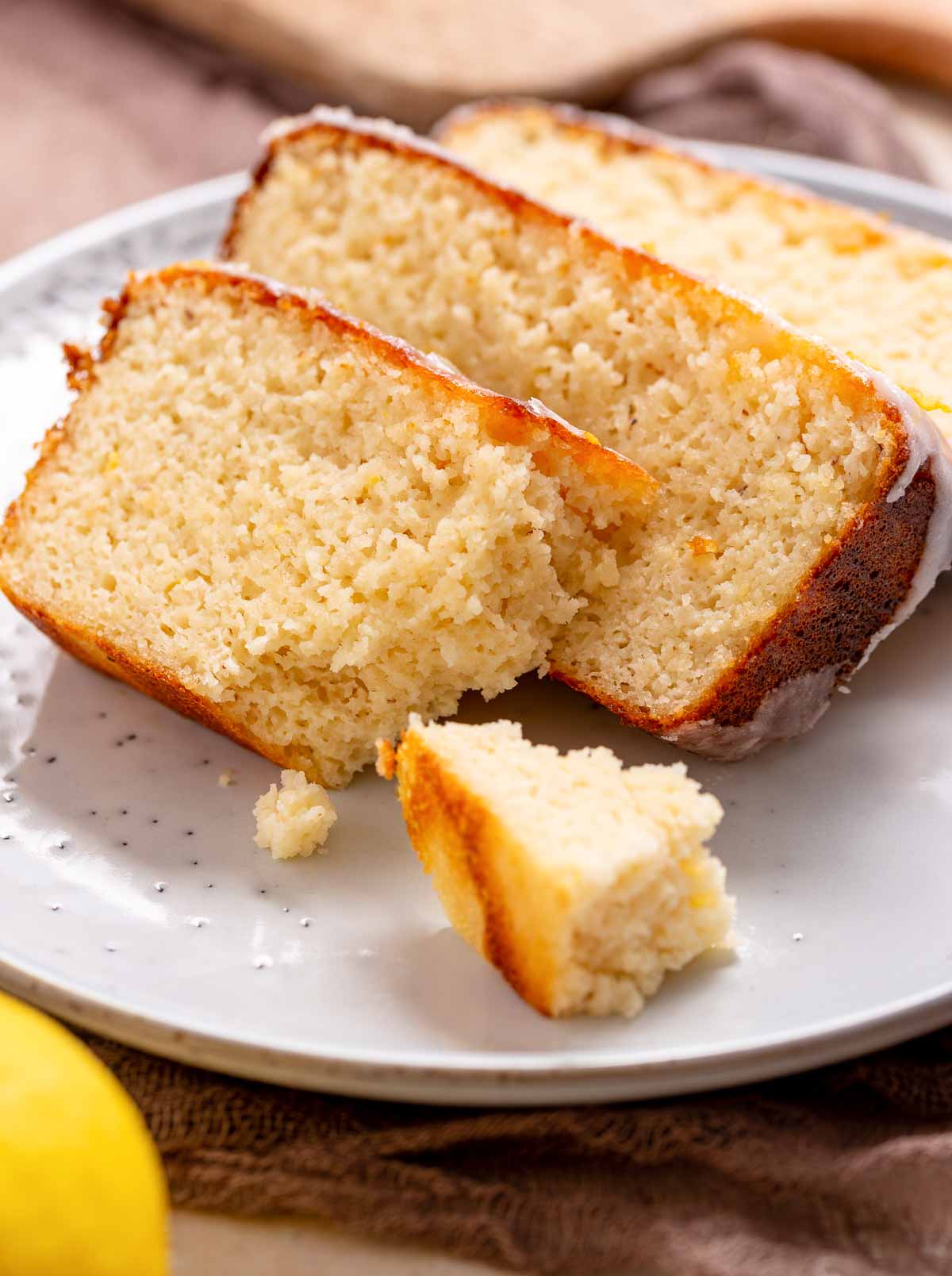 A keto iced lemon loaf that is sliced on a plate.