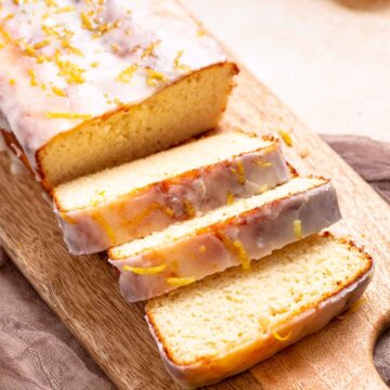 A keto iced lemon loaf that is sliced on a cutting board.