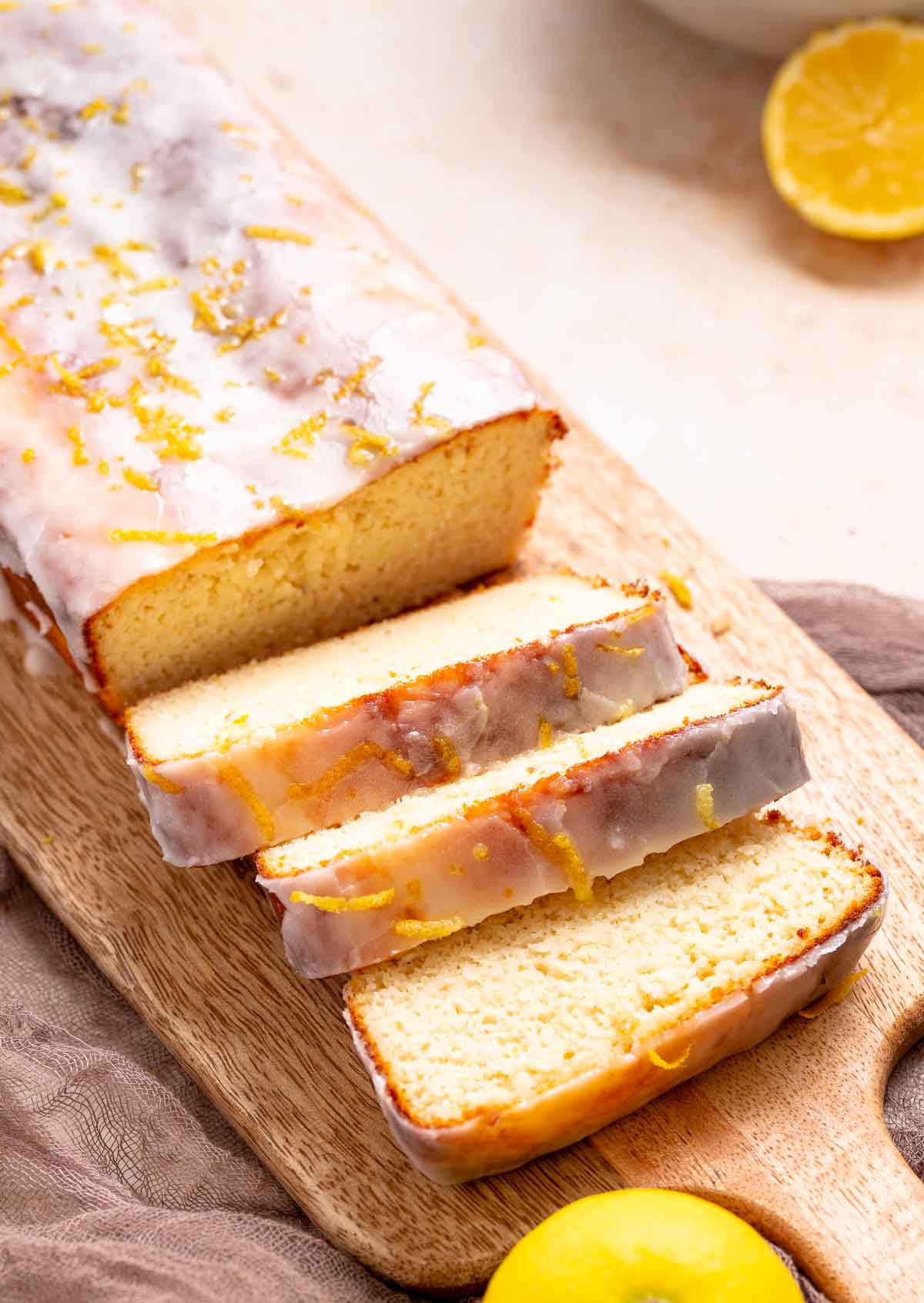 An iced lemon loaf that is sliced on a cutting board.