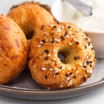 Keto bagels on a plate with a bowl of cream cheese.