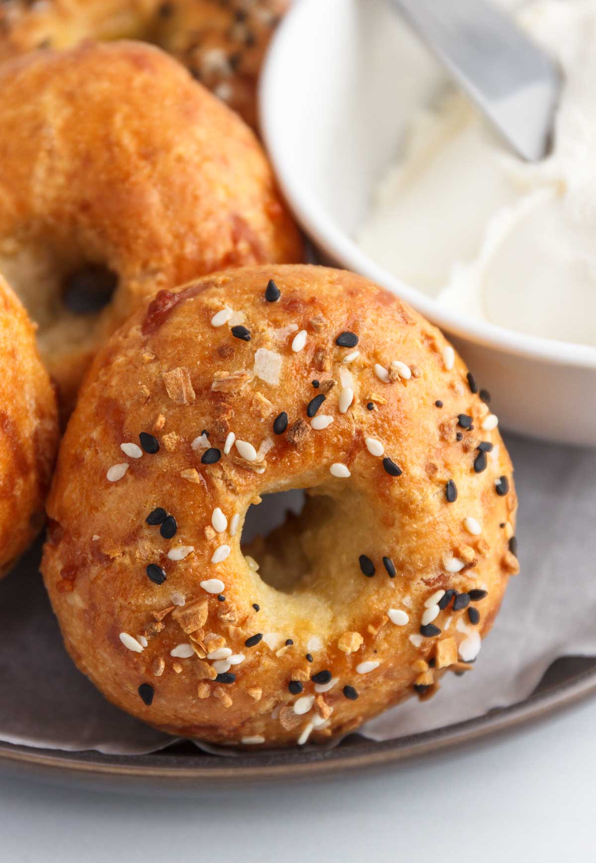 Keto bagels on a plate with a bowl of cream cheese.