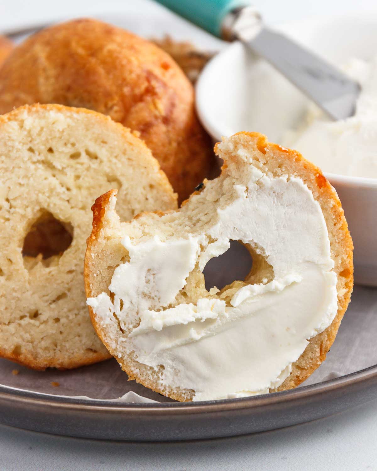 A low carb bagel half with cream cheese spread on it.