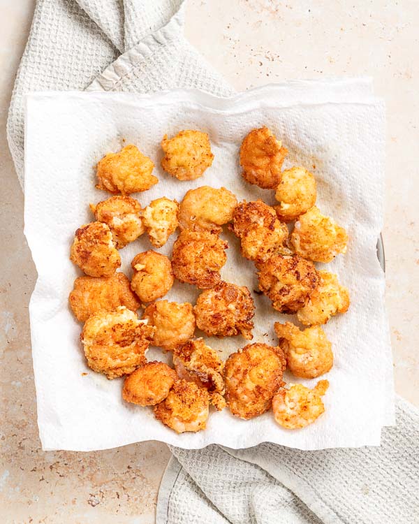 Setting fried shrimp on paper towel to blot excess oil.