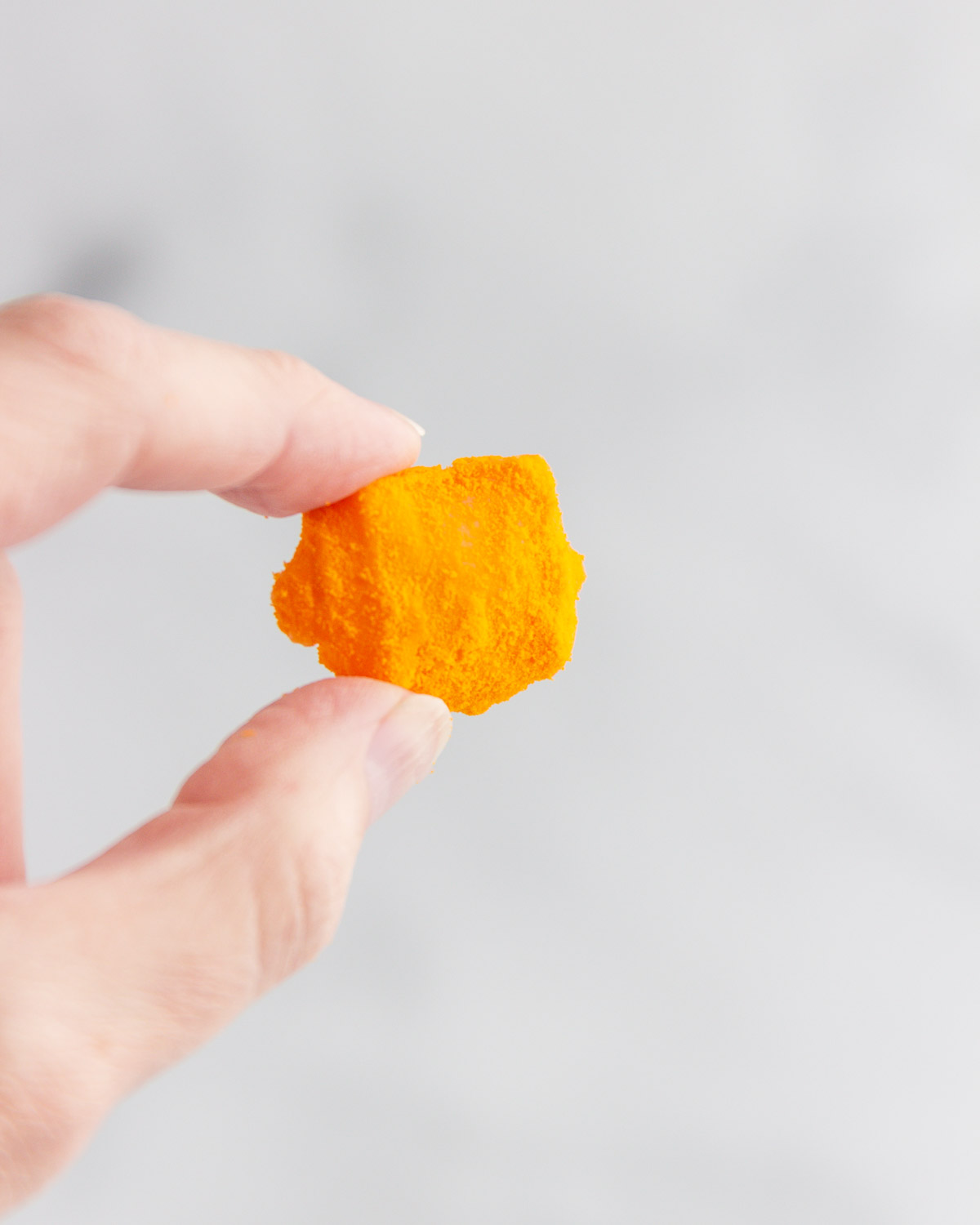 A hand holding one keto cheese puff.