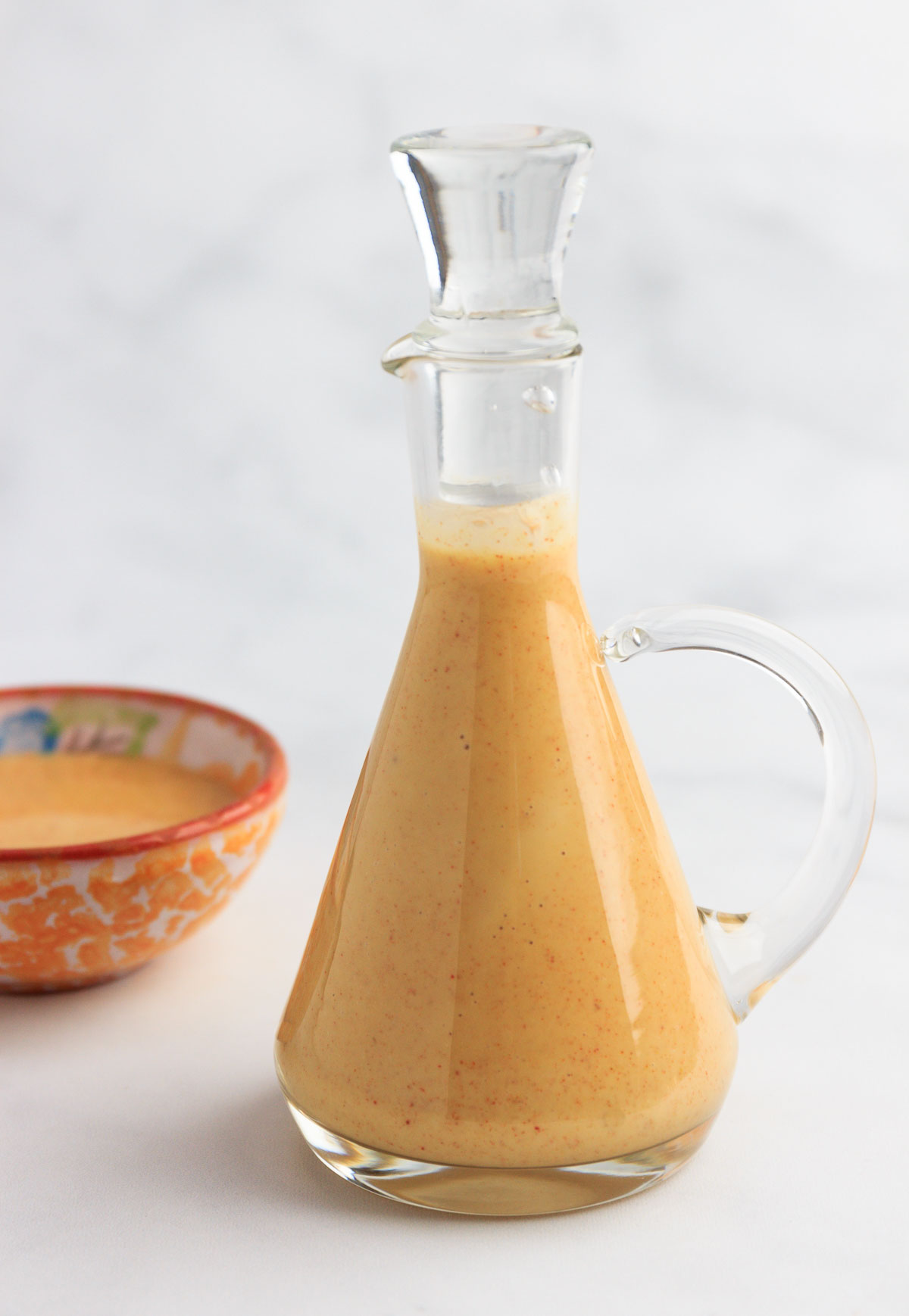 A small glass pitcher with keto honey mustard dressing inside.