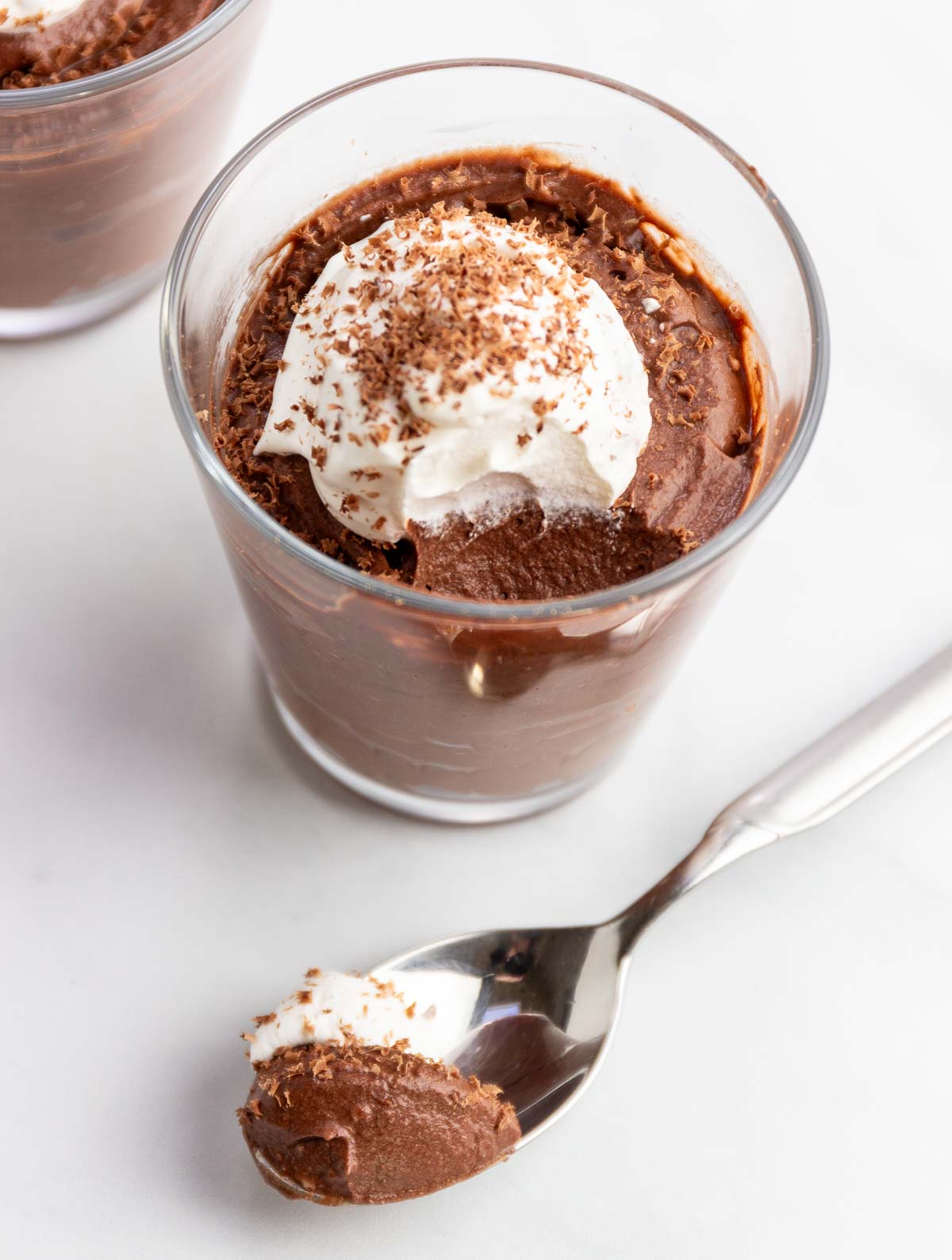 Two small glasses od chocolate coconut mousse with a spoonful of it  next to the glass.