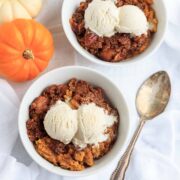 Two Bowls of keto pumpkin crisp with a scoop of vanilla ice cream on top.