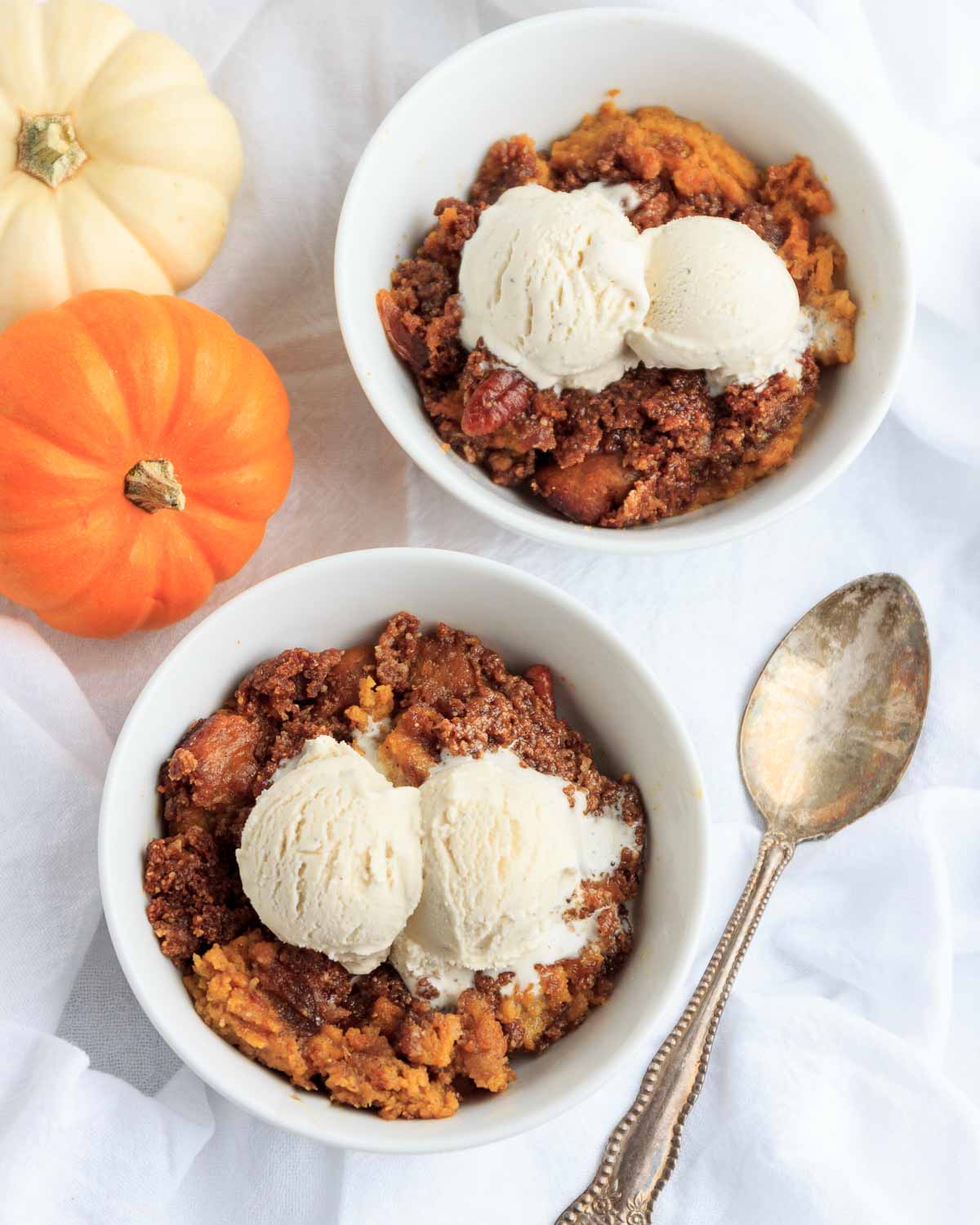 Two Bowls of keto pumpkin crisp with a scoop of vanilla ice cream on top.